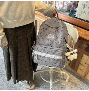 Detalle de una mochila de pana gris para niña con ribete de encaje y colgante de conejo