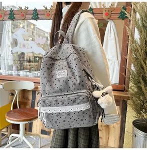 Vista detallada de mochila de pana gris con patrones de lazos en entorno acogedor