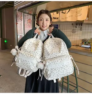 Vista lifestyle de la mochila blanca estilo preppy con patrones de corazones y dijes