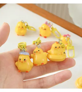 Close-up of cute 3D yellow chick keychain pendants held in hand to show detail and scale