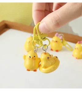 Close-up view of a hand holding a cute yellow 3D resin chick keychain accessory