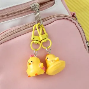 Adorable 3D yellow chick keychain charms hanging on a pink school backpack zipper