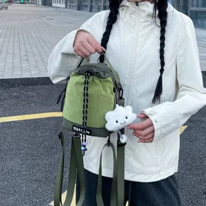 Green grid drawstring backpack with cute cloud plush pendant, casual small shoulder bag for daily use.