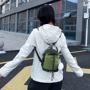 Detail view of a stylish mini green drawstring backpack crossbody bag with cute plush pendant.