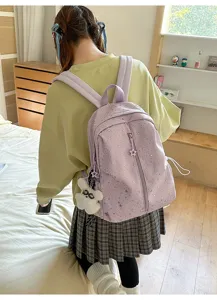 Mochila escolar morada con estampados de estrellas plateadas llevada por una chica