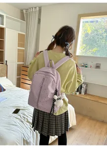 Vista trasera de una estudiante con mochila morada de estrellas y colgante de conejo