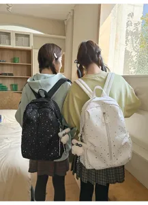 Detalle de dos mochilas con estampado de cielo estrellato usadas por estudiantes en casa.