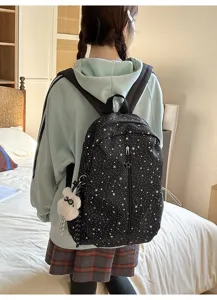 Primer plano de una modelo con mochila negra de cielo estrellado y amuleto conejo