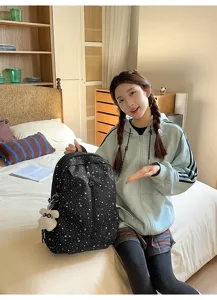 Primer plano de una mochila negra con estrellas llevada por una modelo en un cuarto