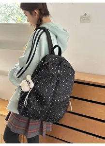 Mochila escolar negra con estampado de estrellas llevada por una modelo en entorno casual