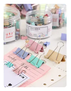 Detalle de clips metálicos de colores Morandi en papel de cuaderno para la oficina