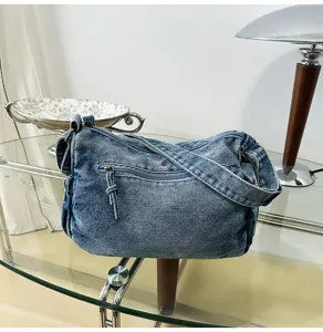 Gedetailleerde close-up opname van de gewassen denim schoudertas met ritsvak en textuur.