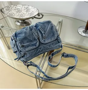 Gedetailleerd shot van casual gewassen denim crossbody schoudertas met zakken en riem.