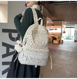 Detalle de una mochila linda con estampados de corazones y mariposas y encaje