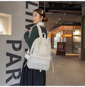 Modelo luciendo una mochila blanca con patrón de lazos y un colgante de panda