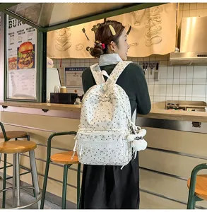 Vista de una chica con una mochila blanca de estilo universitario con corazones en un café