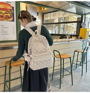 Chica con una mochila crema de estilo preppy con corazones en una foto de café