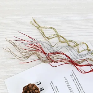 Primo piano di rami decorativi ondulati ricoperti di glitter in oro, argento e rosso
