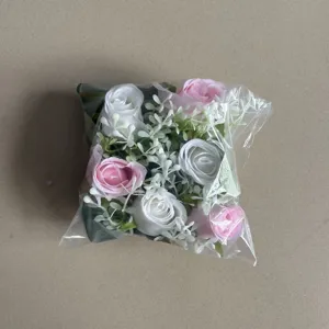 Detail view of artificial rose flower wreath in clear package, pink and white floral decor for home.