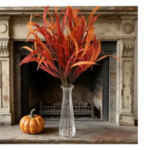 Artificial autumn eucalyptus leaves bouquet in clear glass vase with mini pumpkin decor.
