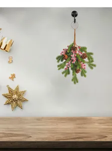 Christmas wall hanging featuring pine needles, pine cones, and red berries in a home setting