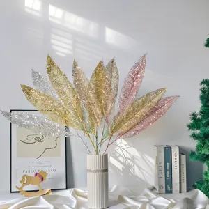 Nahaufnahme von gold- und silbern glitzernden hohlen Blättern in einer weißen Vase