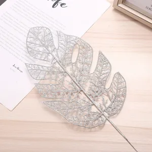 Detailed close-up of silver glitter monstera leaf decoration for Christmas tree and floral arrangement.