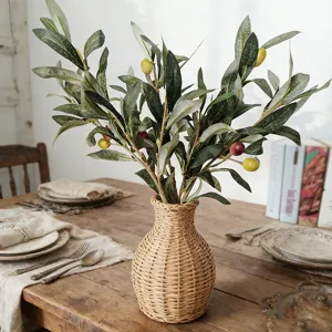 Branches d'olivier artificielles avec fruits et vase tissé pour décoration d'intérieur chic.