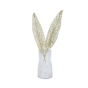 Eleganti foglie di Natale dorate e glitterate in un vaso di vetro per decorazione