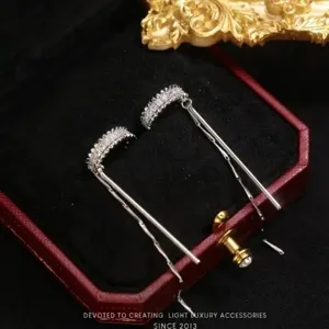 Detail of silver-tone tassel ear bone clips with sparkling zircons on velvet box