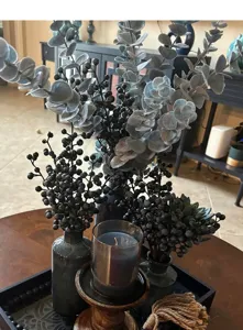 Artificial dark berry branches in a decorative vase for elegant home interior styling.
