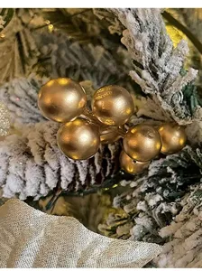 Macro detail view of golden artificial berries on a snow-dusted pine branch texture