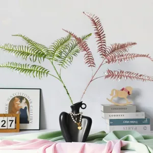 Vue détaillée de branches de fougère à paillettes dans un vase buste noir élégant