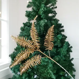 Vue détaillée d'une branche de fougère dorée scintillante sur un sapin de Noël