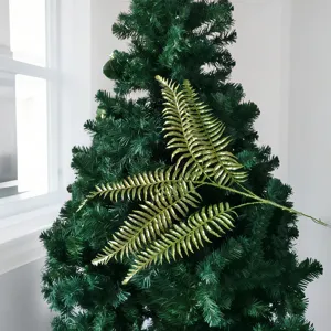 Vue détaillée d'une branche de fougère dorée à paillettes sur un sapin de Noël vert