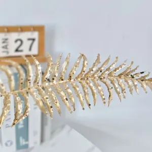 Gros plan détaillé d'une feuille de fougère dorée à paillettes pour décor de Noël