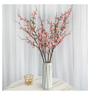 Détail de fleurs de pêcher artificielles roses réalistes dans un vase en céramique blanc élégant