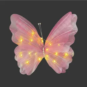 Detailansicht eines rosa leuchtenden Gazeschmetterlings mit warmen LED-Lichtern und Perlen