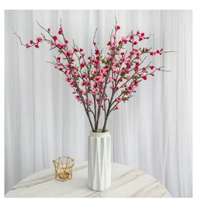 Vue détaillée de branches de fleurs de pêcher roses dans un élégant vase blanc cannelé