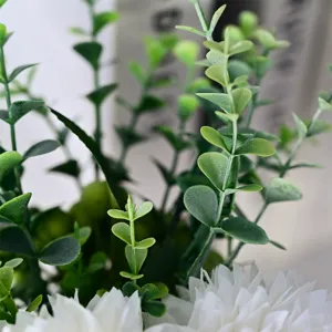 Primo piano di crisantemi artificiali bianchi e rami di eucalipto per decorazioni