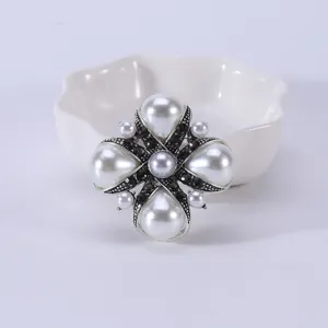 Detailed macro shot of vintage silver cross brooch with pearls and black crystals