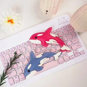 Detail of creative handmade leather orca keychains on a cute keyboard background