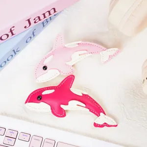 Close-up of cute leather whale charms with detailed stitching and soft colors.