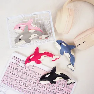 Detailed view of colorful leather orca keychains displayed with lifestyle props like a keyboard