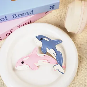 Macro view showing the detailed stitching on pink and blue leather orca whale keychains
