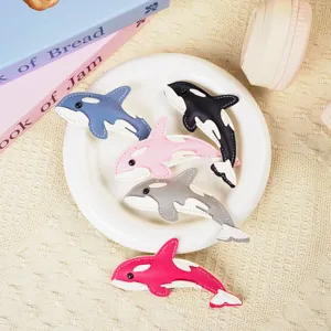 Five different colored leather whale keychains displayed on a white ceramic plate