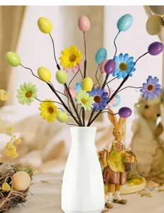 Easter decorative branches with colorful eggs and daisies in a white ceramic vase