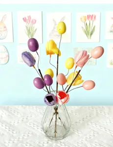 Detailed view of colorful Easter egg and tulip decorative branches in a glass vase