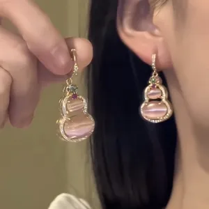 Detailed close-up of pink cat-eye stone double gourd earrings with gold accents.