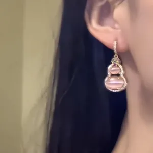 Elegant close-up of a pink cat's eye gourd earring featuring a minimalist Chinese design style.